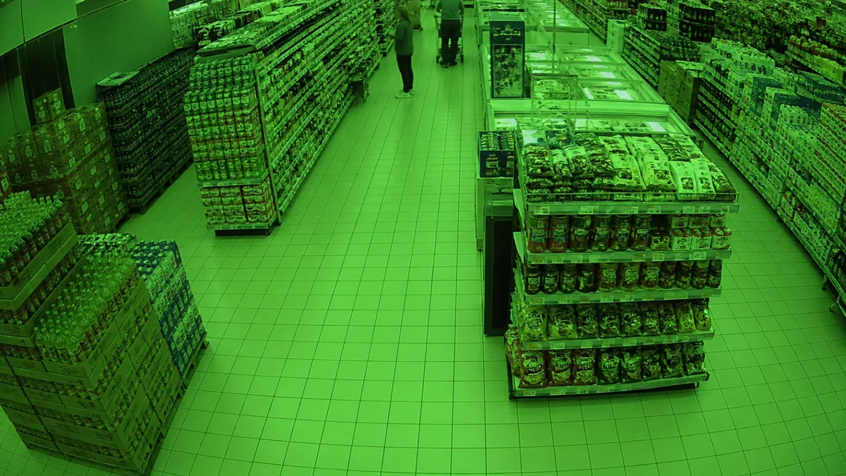 Colour cast degradation in a supermarket aisle CCTV view with an abnormal green tint.