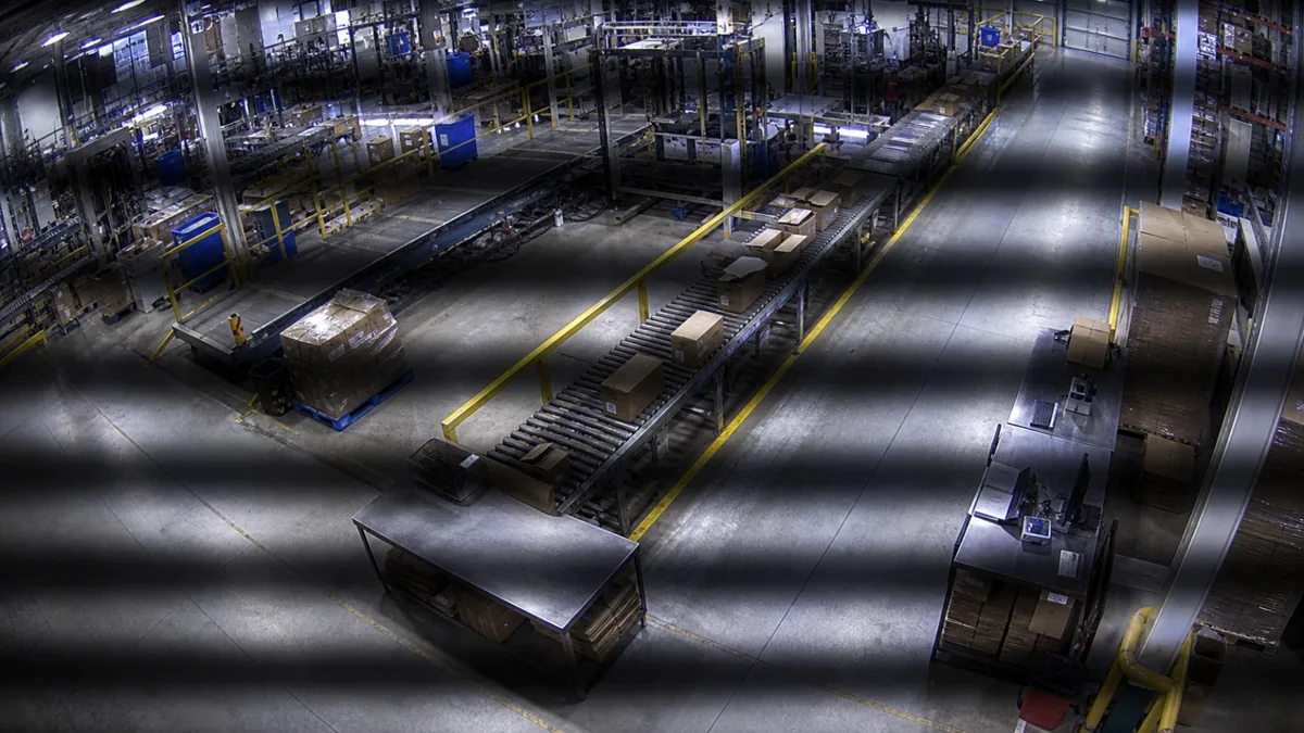 Flicker degradation in a factory packaging line CCTV view with rolling horizontal bands.