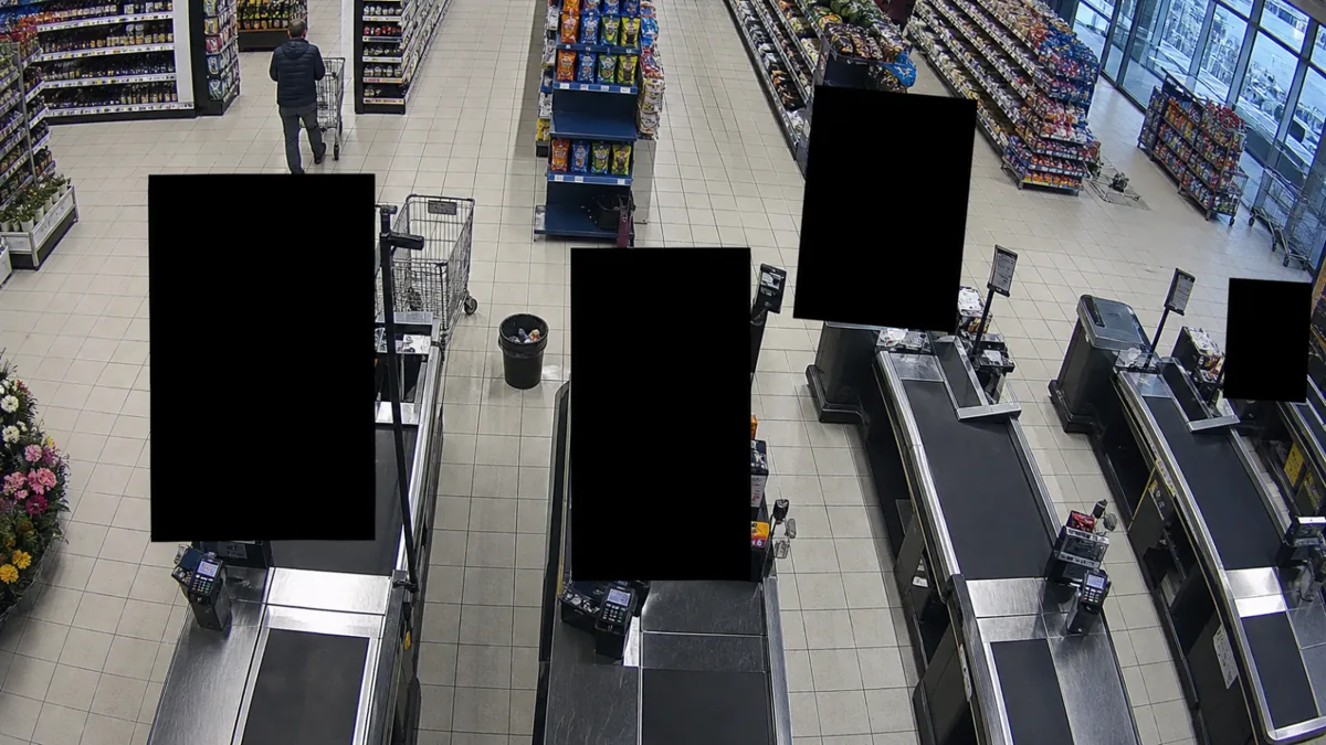 Unexpected privacy mask degradation in a supermarket checkout CCTV view, with black blocks hiding payment areas.