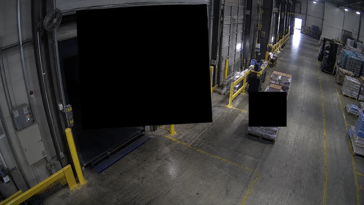 Unexpected privacy mask degradation in a loading dock CCTV view, with black blocks hiding dock doors.